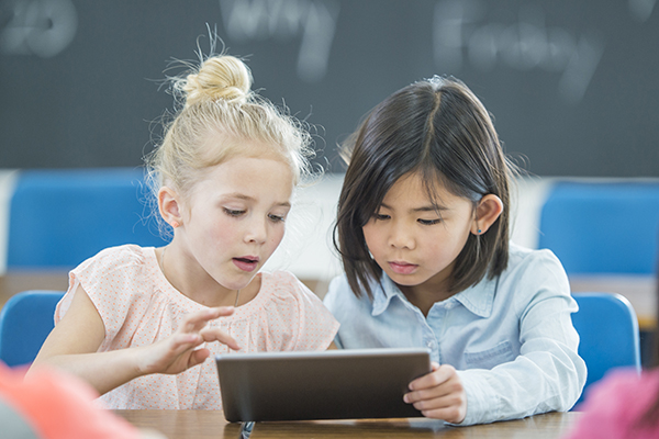Two elementary school students share a tablet