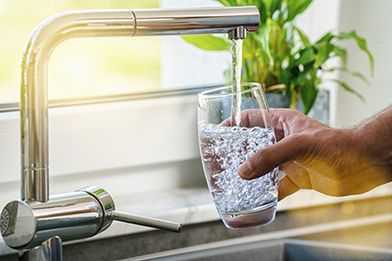 Person filling a glass of water from the tap