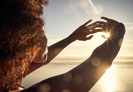 Woman on beach facing sun