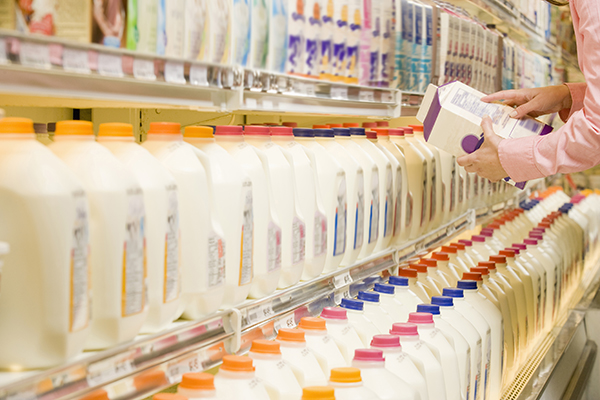 Women checking ingredients on the back of a milk jug.